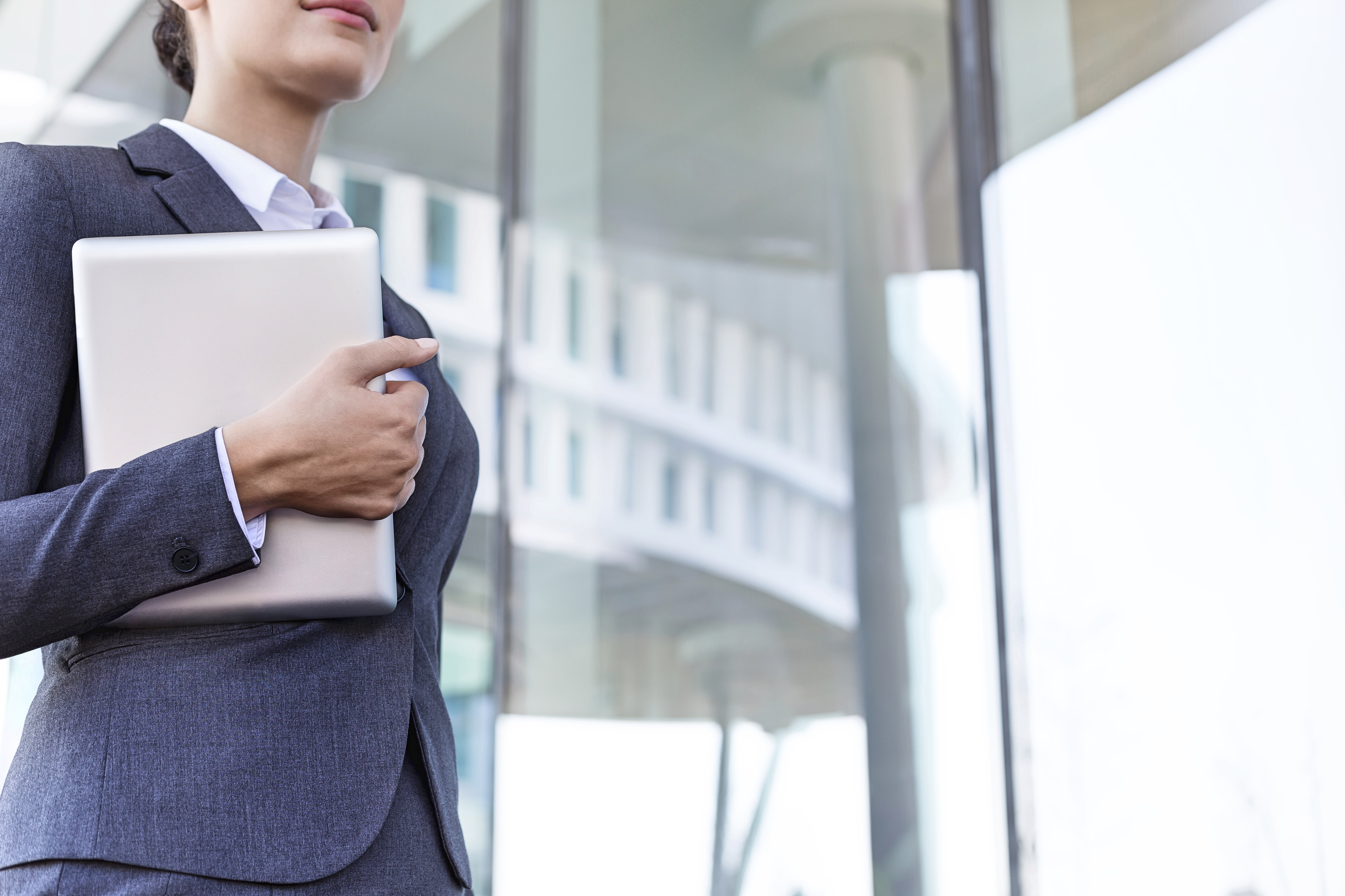 Female solicitor dressed in a navy suit, white shirt, and carrying a latop reflecting coaching lawyers for partnership in law firms