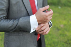 A solicitor in a grey suit and red tie, tugging at their cuff, perhaps demonstrating some self hesitancy which is intended to reflect the benefits of training for solicitors.