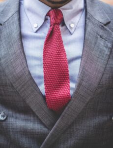 Solicitor or partner in a grey jacket, black shirt, and red tie attending management training for lawyers.