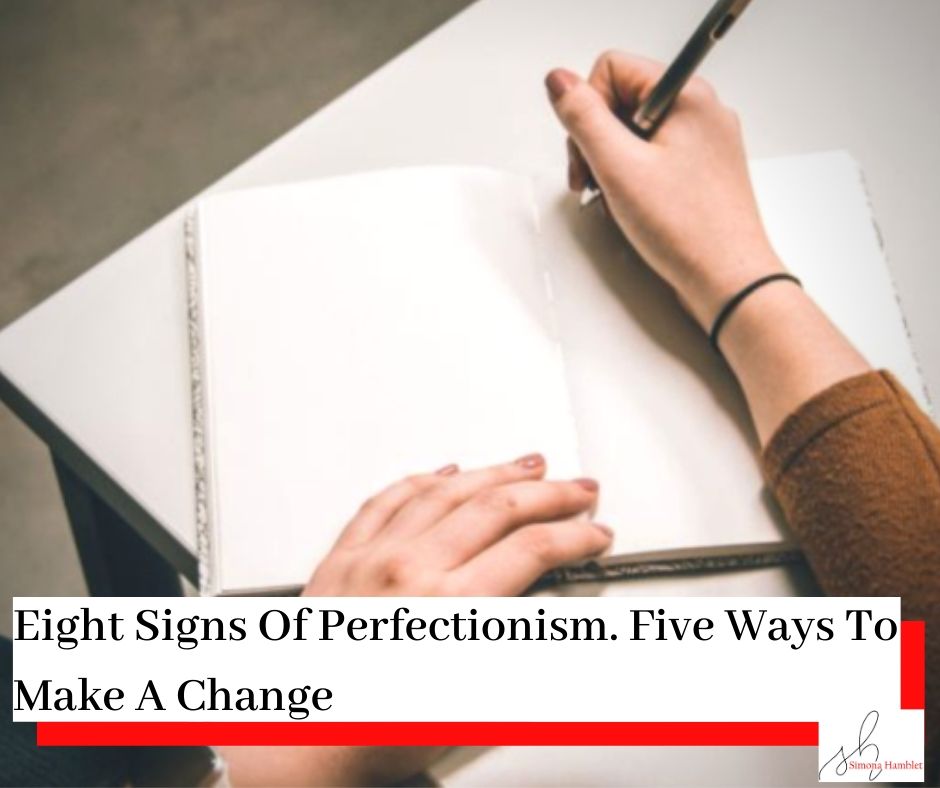 Person writing in a blank book on a desk wearing a brown jumper with the title Eight Signs Of Perfectionism - Five Ways To Make A Change