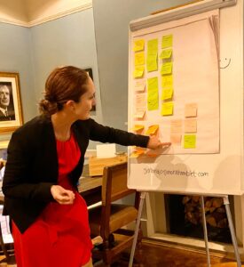 Image of Simona Hamblet at a venue with a white board covered in post it note stickers. Reflecting training for solicitors and legal executives.