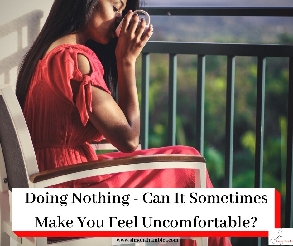 Woman in red sat on a balcony drinking coffee with the title Doing Nothing - Can It Sometimes Make You Feel Uncomfortable?